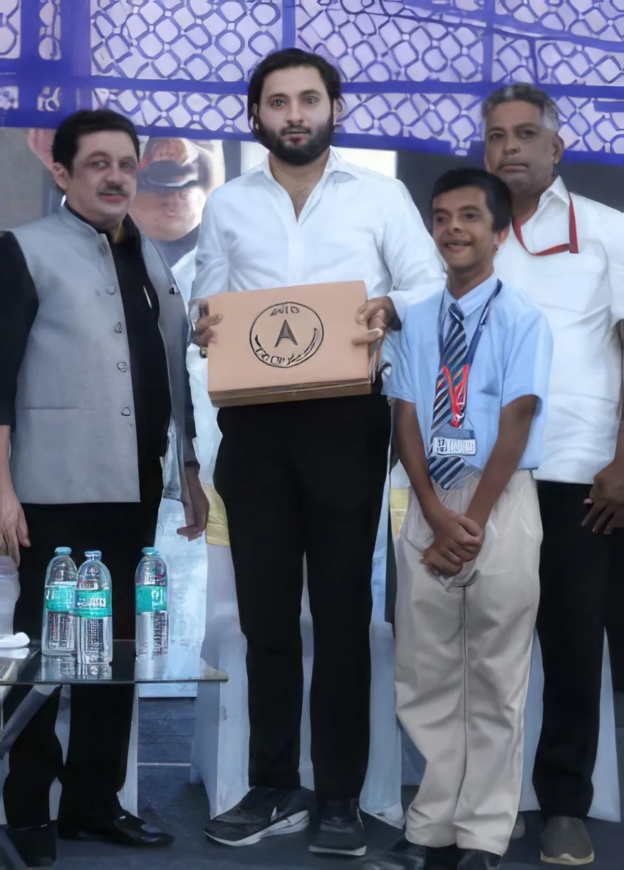 Salmaan Ahmed with a student receiving a school kit
